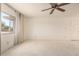 Cozy carpeted living room with neutral walls, a ceiling fan, and a large window with sheer curtains at 11627 S Iroquois Dr, Phoenix, AZ 85044