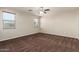 Cozy bedroom features two bright windows, neutral paint, a ceiling fan, plush carpeting, and ample natural light at 12029 W Overlin Ln, Avondale, AZ 85323