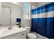 Bathroom features a white vanity with mirror, a window, toilet and tub with blue curtain at 15070 W Garfield St, Goodyear, AZ 85338