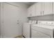 Functional laundry room with washer, dryer, cabinets, and access door to the backyard at 16147 W Central St, Surprise, AZ 85374