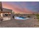 Stunning backyard with pool, barbecue, and desert landscaping, set against a beautiful sunset sky at 17562 W Desert Sage Dr, Goodyear, AZ 85338
