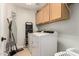 Functional laundry room with front-load washer and dryer, ample storage cabinets, and cleaning supplies at 17562 W Desert Sage Dr, Goodyear, AZ 85338