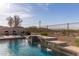 Stunning backyard featuring a rock waterfall into the pool, set against a backdrop of scenic desert landscape at 17562 W Desert Sage Dr, Goodyear, AZ 85338