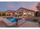Backyard showcasing a modern house, covered patio, and a beautiful blue pool with a raised step entry at 17562 W Desert Sage Dr, Goodyear, AZ 85338