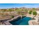 A sparkling swimming pool with waterfall feature, stone coping, and views of the desert landscape at 17562 W Desert Sage Dr, Goodyear, AZ 85338