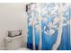 This bathroom features a toilet with decorative basket on top and a blue and white floral shower curtain at 17851 W Calavar Rd, Surprise, AZ 85388