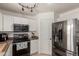 Kitchen showcasing stainless steel appliances, white cabinets, and a dark tiled backsplash at 17851 W Calavar Rd, Surprise, AZ 85388