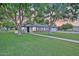Charming single-story home featuring a lush green lawn, mature shade trees, and a welcoming front porch with rocking chairs at 1886 S 141St Pl, Gilbert, AZ 85295