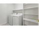 Well-lit laundry room with a white washer, dryer, and convenient shelving at 19010 N 35Th Way, Phoenix, AZ 85050