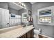 Updated bathroom featuring a quartz countertop, wood cabinets, and a large window with natural light and shutter at 19903 E Augustus Ave, Queen Creek, AZ 85142