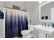 Cozy bathroom with pedestal sink, ceramic tile floors, a framed mirror, and a decorative shower curtain at 19903 E Augustus Ave, Queen Creek, AZ 85142