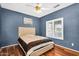 Bedroom with hardwood floors, ceiling fan, window with blinds and a blue accent wall at 19903 E Augustus Ave, Queen Creek, AZ 85142