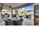 Covered patio with grill, dining table, stone countertops, ceiling fan and view of grassy back yard at 19903 E Augustus Ave, Queen Creek, AZ 85142