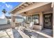 Covered patio with stone pavers, ceiling fan, and striped rocking chairs providing a relaxing outdoor space at 19903 E Augustus Ave, Queen Creek, AZ 85142
