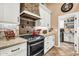 Close-up of kitchen with a gas range, custom hood, and a doorway leading to the laundry area at 19903 E Augustus Ave, Queen Creek, AZ 85142