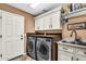 Functional laundry room with modern washer and dryer, sink with white cabinetry, and overhead storage at 19903 E Augustus Ave, Queen Creek, AZ 85142
