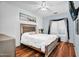 Main bedroom with ceiling fan, hardwood floors, a window with shutters and curtains, and a white duvet cover at 19903 E Augustus Ave, Queen Creek, AZ 85142
