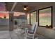 Covered porch featuring cozy rocking chairs, ceiling fan, and views of the backyard with a tranquil sunset backdrop at 19903 E Augustus Ave, Queen Creek, AZ 85142