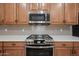 Close-up of stainless steel oven range and microwave with custom wood cabinetry at 20453 W Daniel Pl, Buckeye, AZ 85396