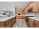 Open kitchen with stainless appliances, wood cabinets, quartz counters, and island with plank flooring at 20453 W Daniel Pl, Buckeye, AZ 85396