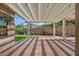 Inviting covered patio overlooking lush backyard lawn with mature trees and brick wall surround at 20453 W Daniel Pl, Buckeye, AZ 85396