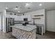 Well-lit kitchen showcasing stainless steel appliances, granite countertops, and a stylish mosaic island at 21582 W Cocopah St, Buckeye, AZ 85326