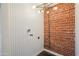 Charming laundry room features brick accent wall, herringbone wallpaper, modern light fixture, and utility connections at 2225 E Monterosa St, Phoenix, AZ 85016