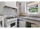 Galley kitchen with older appliances, white cabinetry and trim, a stainless steel sink, and window to the backyard at 2230 N 12Th St # Rear, Phoenix, AZ 85006