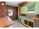 Retro kitchen featuring wood paneling, a breakfast bar, and classic green and yellow cabinets at 2230 N 12Th St # Rear, Phoenix, AZ 85006