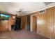 Living room with wood paneled walls, brick fireplace, ceiling fan, and view of adjacent room at 2230 N 12Th St # Rear, Phoenix, AZ 85006