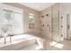 Luxurious bathroom features a soaking tub, frameless shower, and travertine tile at 22756 N 91St Way, Scottsdale, AZ 85255