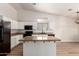 Open-concept kitchen showcasing white cabinets, granite counters, an island, and black appliances at 30212 N Sunray Dr, San Tan Valley, AZ 85143