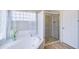 Bright bathroom featuring a soaking tub, a glass-enclosed shower, and tile flooring at 3921 W Jasper Dr, Chandler, AZ 85226