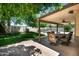 Covered back patio features an outdoor dining area, ceiling fan, and tranquil views of the backyard and pool at 5132 E Grandview Rd, Scottsdale, AZ 85254