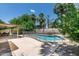Beautiful backyard features a pool with a safety fence, mature landscaping, and a covered patio area at 5132 E Grandview Rd, Scottsdale, AZ 85254