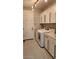 Well-lit laundry room featuring modern appliances, tiled floor and sleek white cabinets offering ample storage space at 5490 W Trenton Way, Florence, AZ 85132