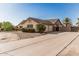 Beige single-story home showcasing desert landscaping, shrubbery, and a concrete driveway at 6032 W Grovers Ave, Glendale, AZ 85308
