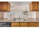 Close-up of traditional kitchen featuring wood cabinets, granite countertops, and stainless steel sink and faucet at 6032 W Grovers Ave, Glendale, AZ 85308