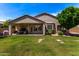 A large backyard featuring a covered patio, lush lawn, and mature landscaping at 7231 W Lone Cactus Dr, Glendale, AZ 85308