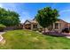 A spacious backyard with mature landscaping, including trees, shrubs, and a covered patio at 7231 W Lone Cactus Dr, Glendale, AZ 85308