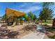 Community playground featuring a covered play structure, slide, and paved walkway on a sunny day at 7231 W Lone Cactus Dr, Glendale, AZ 85308