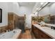 Bathroom featuring a soaking tub, glass shower, dual vanity sinks, and a travertine tile surround at 7272 E Gainey Ranch Rd # 29, Scottsdale, AZ 85258