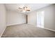 Bright bedroom features neutral carpet and a ceiling fan with easy access to the bathroom at 7439 E Ed Rice Ave, Mesa, AZ 85208