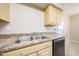 This kitchen features stainless steel sinks, neutral countertops, and light wood cabinets at 7439 E Ed Rice Ave, Mesa, AZ 85208