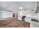 Spacious open-plan kitchen and living area with terracotta tile flooring, white cabinetry, and brick fireplace at 8002 E Whitton Ave, Scottsdale, AZ 85251