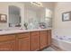 Bathroom with double vanity, tub, framed mirror, and wood cabinets at 839 E Leo Pl, Chandler, AZ 85249