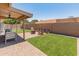This backyard features artificial turf, a paved patio area, a covered area, and a seating arrangement around a fire pit at 9125 E Gelding Dr, Scottsdale, AZ 85260