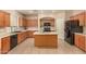 Spacious kitchen features wood cabinets, black appliances, and central island with tile flooring at 9207 W Kirby Ave, Tolleson, AZ 85353