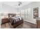 Well-lit bedroom with wood floors, shutters, a bed and a modern, geometric wall hanging at 9532 E Knoll Cir, Mesa, AZ 85207