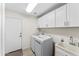 Functional laundry room with white cabinets, modern machines, and a built-in sink at 9532 E Knoll Cir, Mesa, AZ 85207